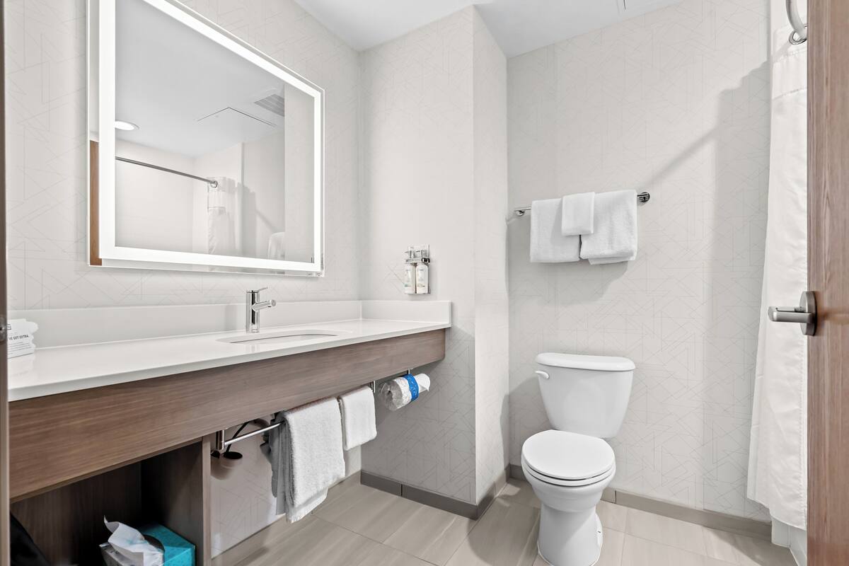 A modern bathroom with a wooden vanity, white sink, and a toilet.