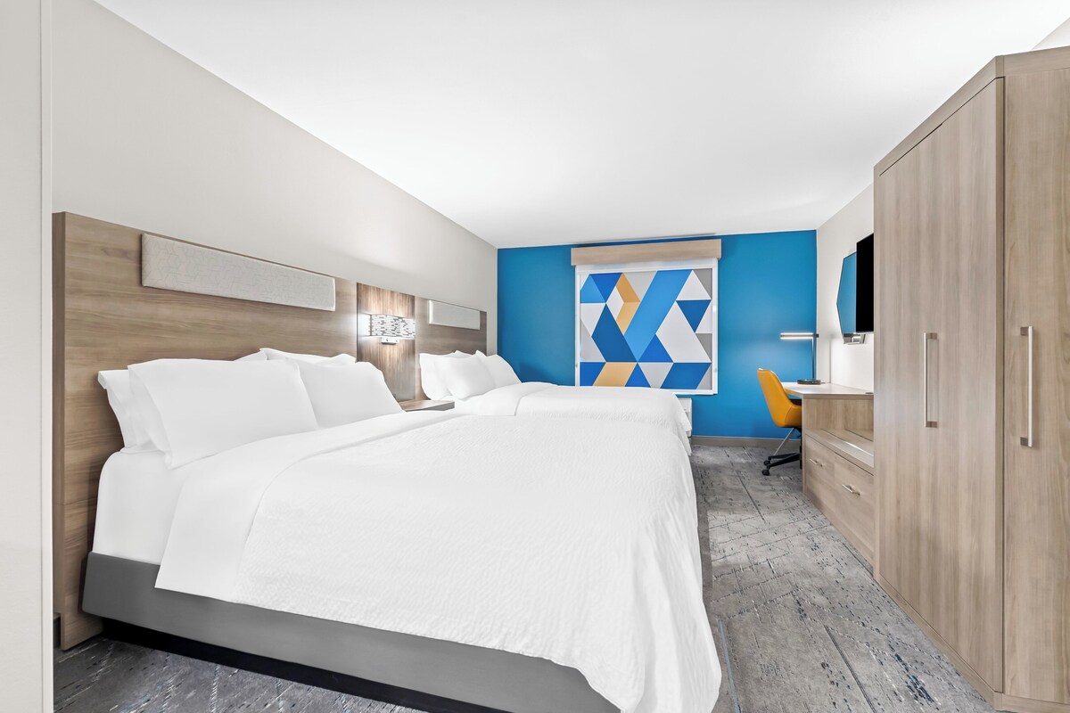 Una camera d'albergo moderna con un letto grande, una scrivania e un armadio.