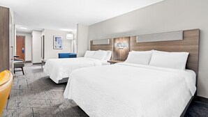A hotel room with two beds, a desk, a chair, and a large window.