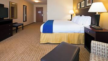 A hotel room with a bed, a desk, a chair, a television, and a lamp.