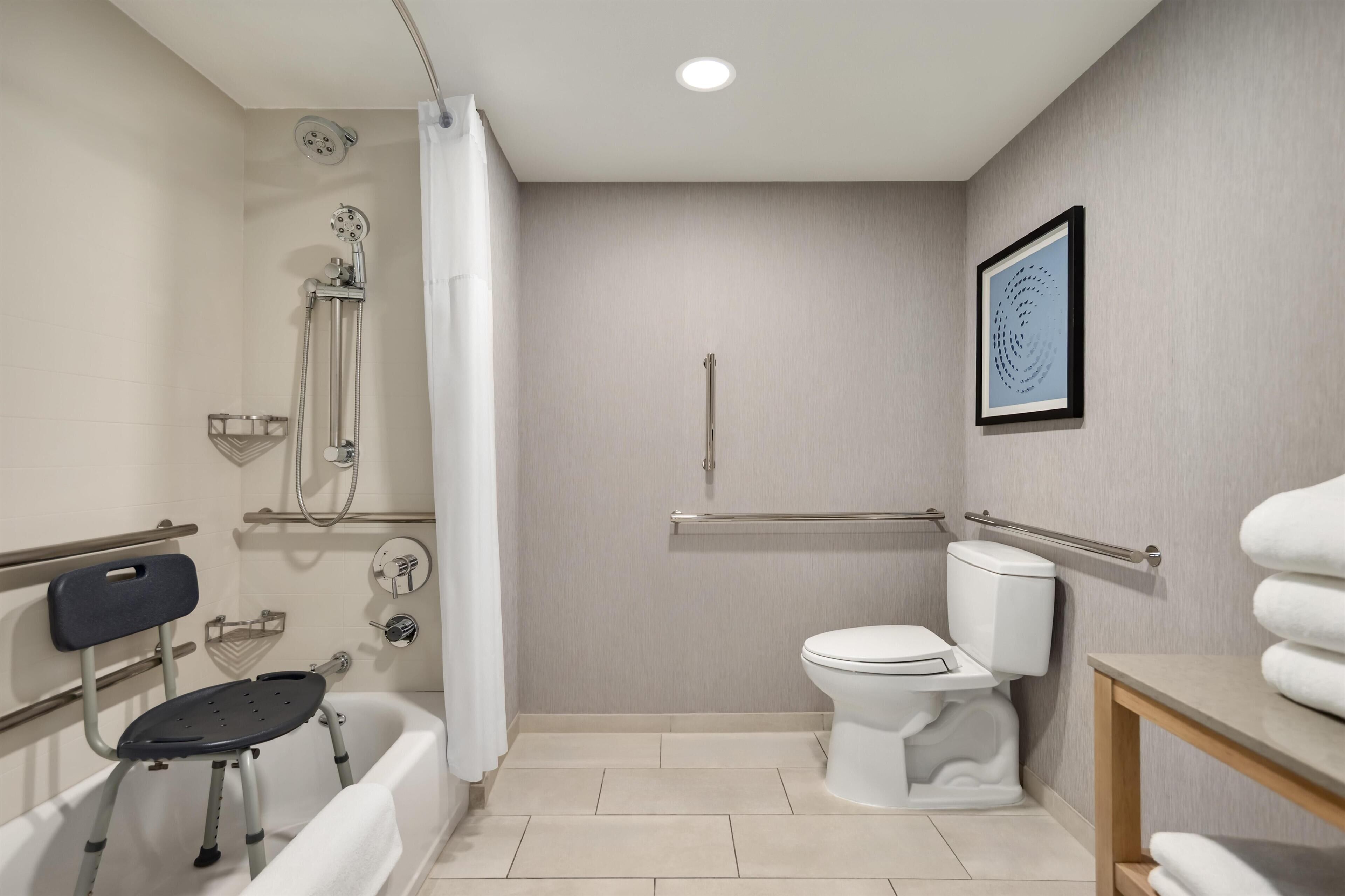 A bathroom with a shower, toilet, and a wheelchair-accessible bench.