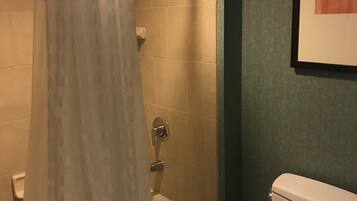 A bathroom with a shower, toilet, and a framed picture on the wall.