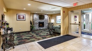 A lobby with a stone fireplace, a reception desk, and a patterned carpet.