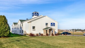 A white building with a green roof, a sign for Cobblestone Inn & Suites, and a phone number.