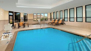 An indoor swimming pool with clear blue water, surrounded by lounge chairs and a table. - Courtyard by Marriott Tyler (Tyler)