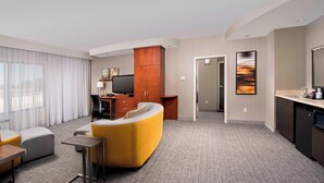 A hotel room with a living area, a kitchenette, a flat-screen TV, and a large window with curtains. - Courtyard by Marriott Tyler (Tyler)