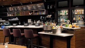 A bar area with wooden furniture, a menu board, and a variety of bottles and glasses. - Courtyard by Marriott Tyler (Tyler)