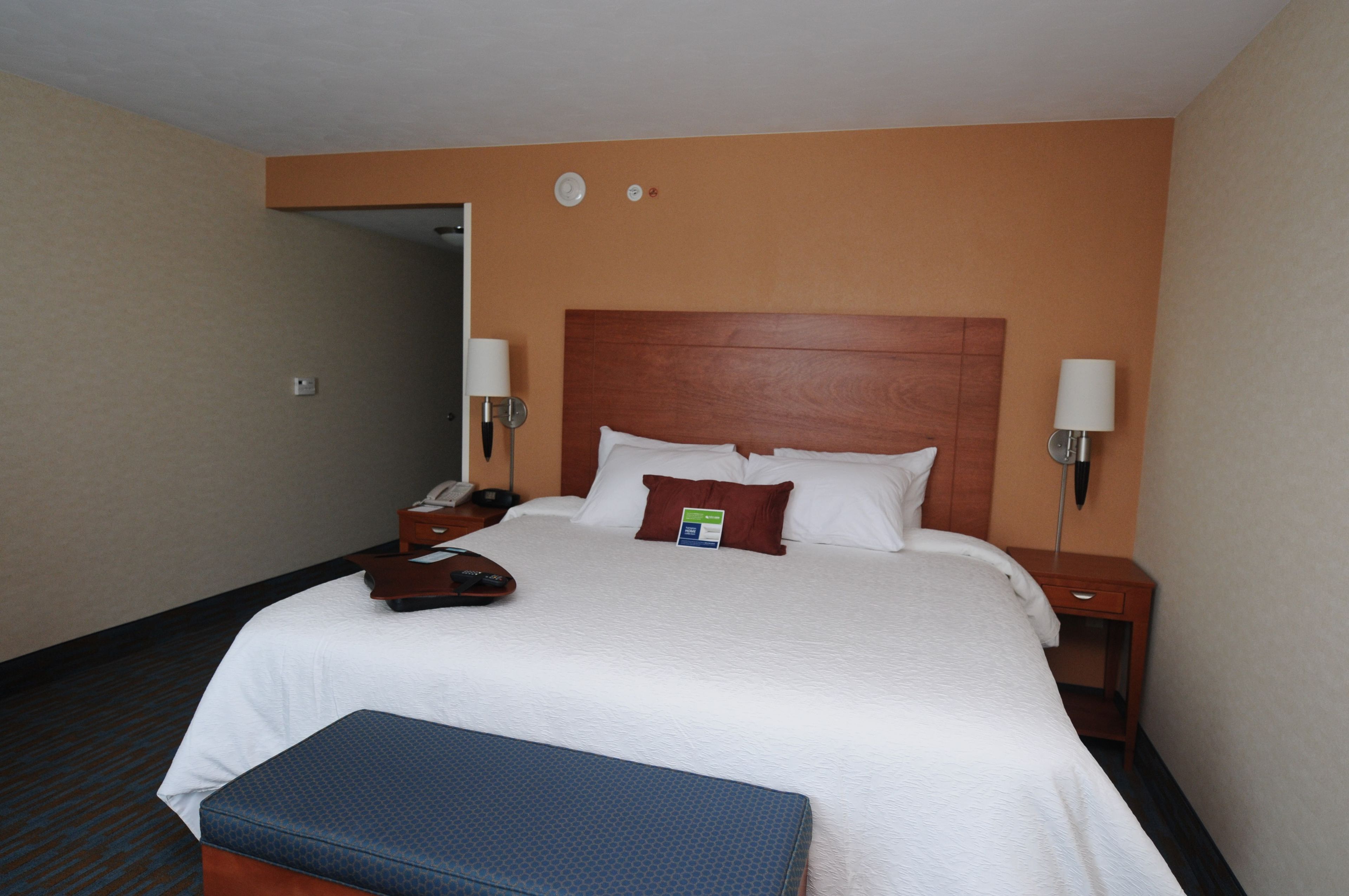 Una habitación de hotel con una cama grande, una mesita de noche, una lámpara y un teléfono.