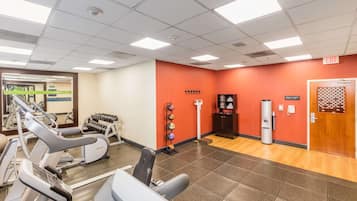 A fitness center with treadmills, weight machines, and a wall-mounted dumbbell rack.