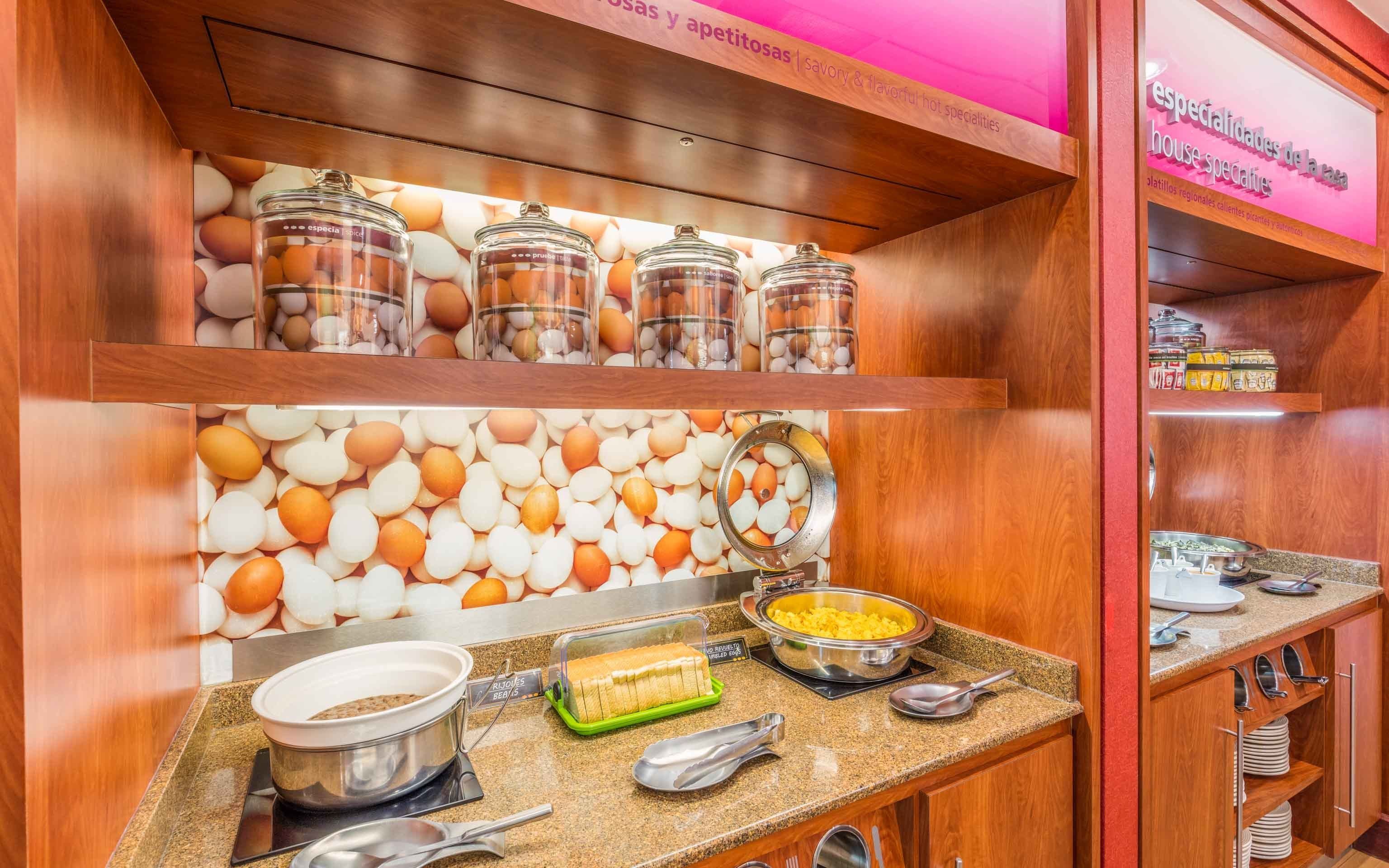A breakfast buffet area with various food items and utensils.