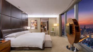 Una habitación de hotel moderna con una cama grande, un escritorio y vistas de la ciudad al atardecer.