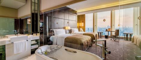 A modern hotel room with a large bathtub, a separate bathroom, a city view, and a desk with a chair.