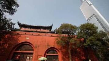 A traditional building with a red facade and a modern skyscraper in the background.