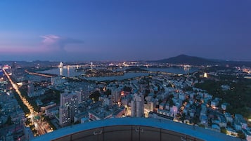 Vista panorámica de una ciudad al atardecer, con un río, edificios y una montaña al fondo.