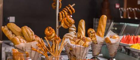 A variety of baked goods including bread, pretzels, and pastries displayed in a buffet setting.
