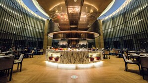Un restaurant moderne doté d’un bar central, de planchers en bois et d’un plafond aux lignes courbes.