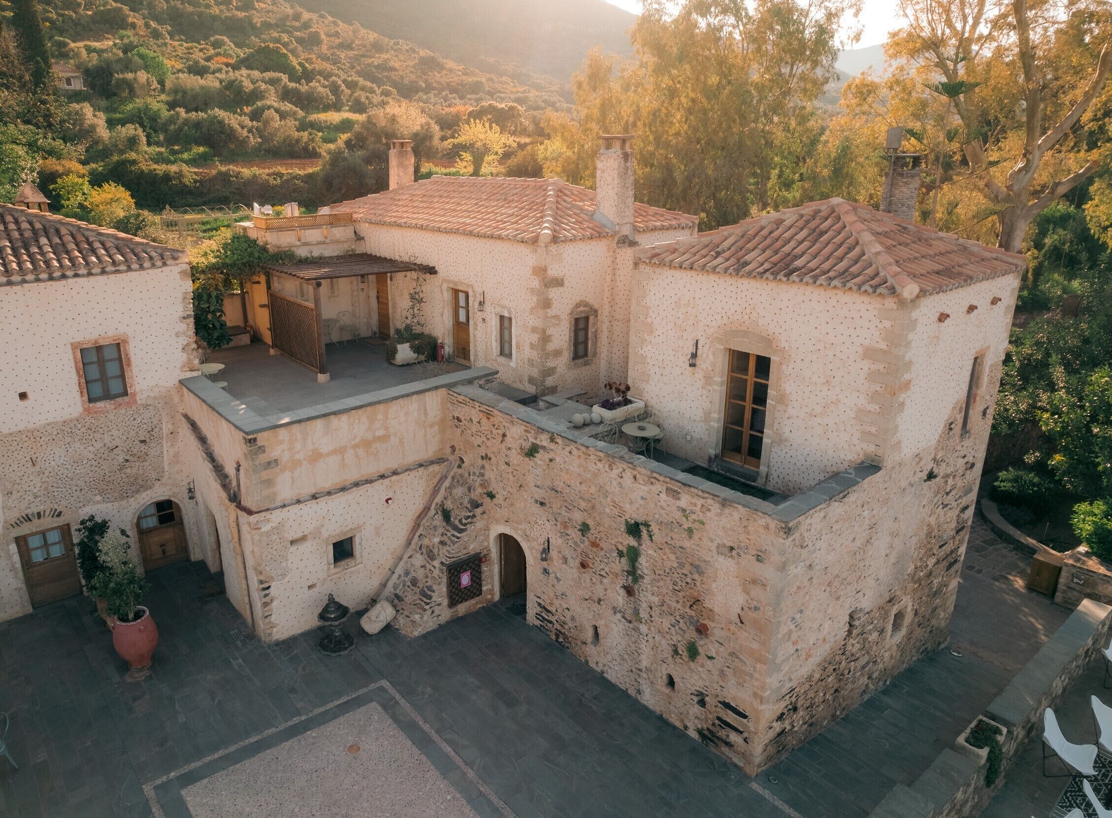 A traditional stone building with a courtyard, featuring a small patio area with outdoor seating and a staircase leading to an upper level.