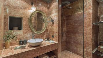 A bathroom with a marble sink, a large mirror, a shower, and a potted plant.
