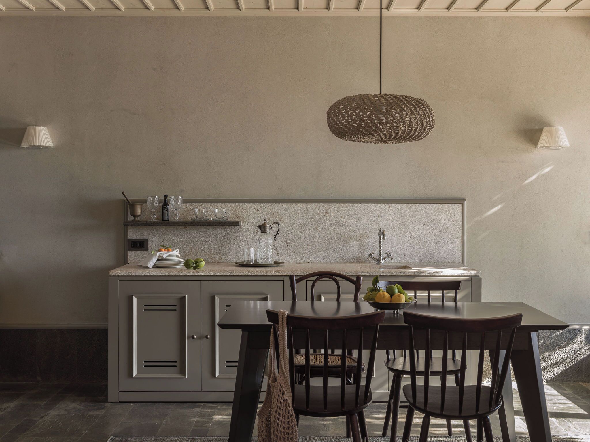 Una cocina moderna con una isla central, una lámpara colgante y un comedor con sillas y una mesa.
