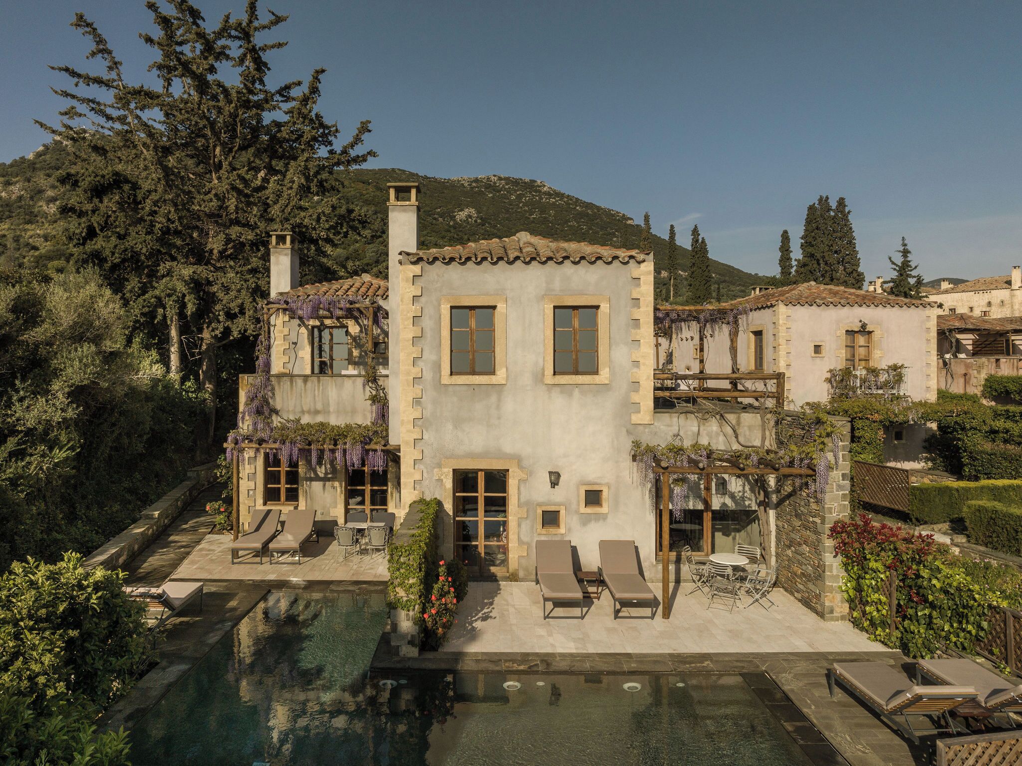 Un edifici de dues plantes amb piscina, zona de seients a l'exterior i jardí.