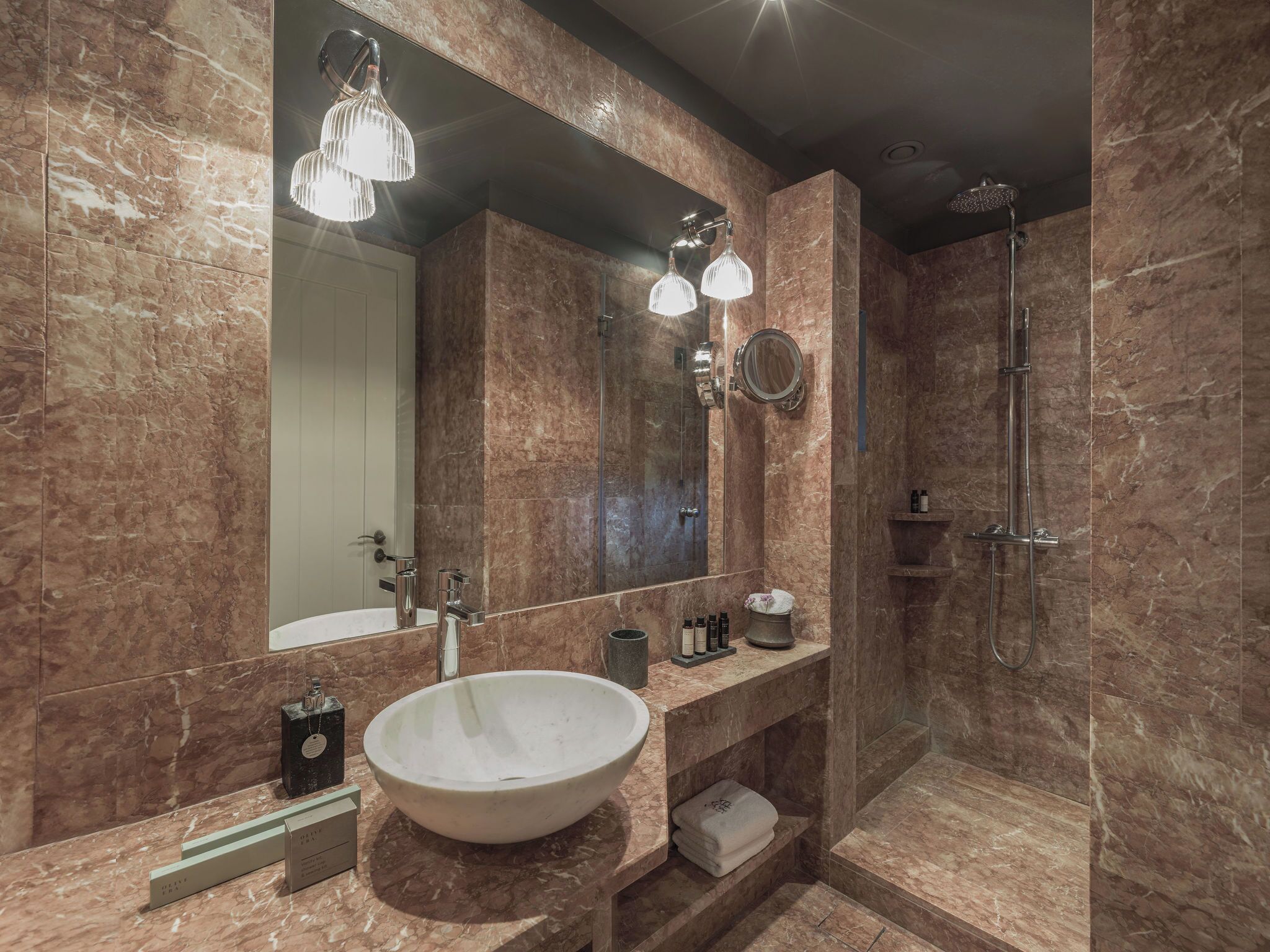 A modern bathroom with a large marble sink, a mirror, and a shower.
