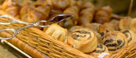 A wicker basket filled with various pastries, including croissants and a poppy seed roll.