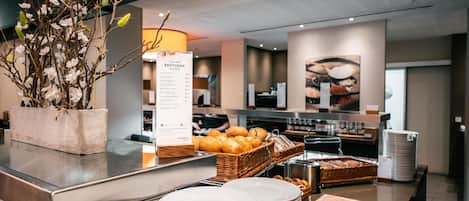 A buffet area with a menu board, bread baskets, and stacked plates.
