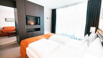 Ein Hotelzimmer mit Bett, Fernseher, Schreibtisch und einer Couch.