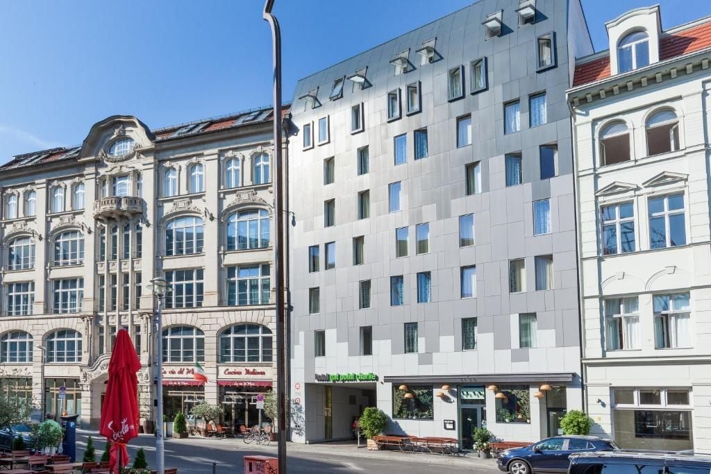 Un edificio de varios pisos con fachada moderna, un restaurante en la planta baja y un paraguas rojo de Coca-Cola.