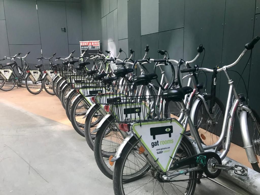 Varias bicicletas estacionadas en un área designada, con un letrero que indica servicio de alquiler de bicicletas.