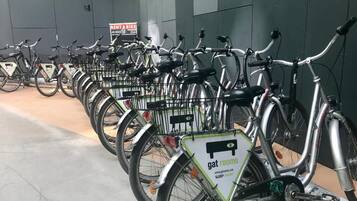A row of bicycles parked in a designated area with a sign indicating a bike rental service.