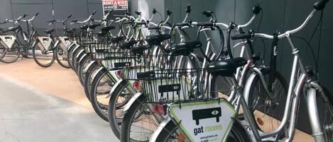 Varias bicicletas estacionadas en un área designada, con un letrero que indica servicio de alquiler de bicicletas.