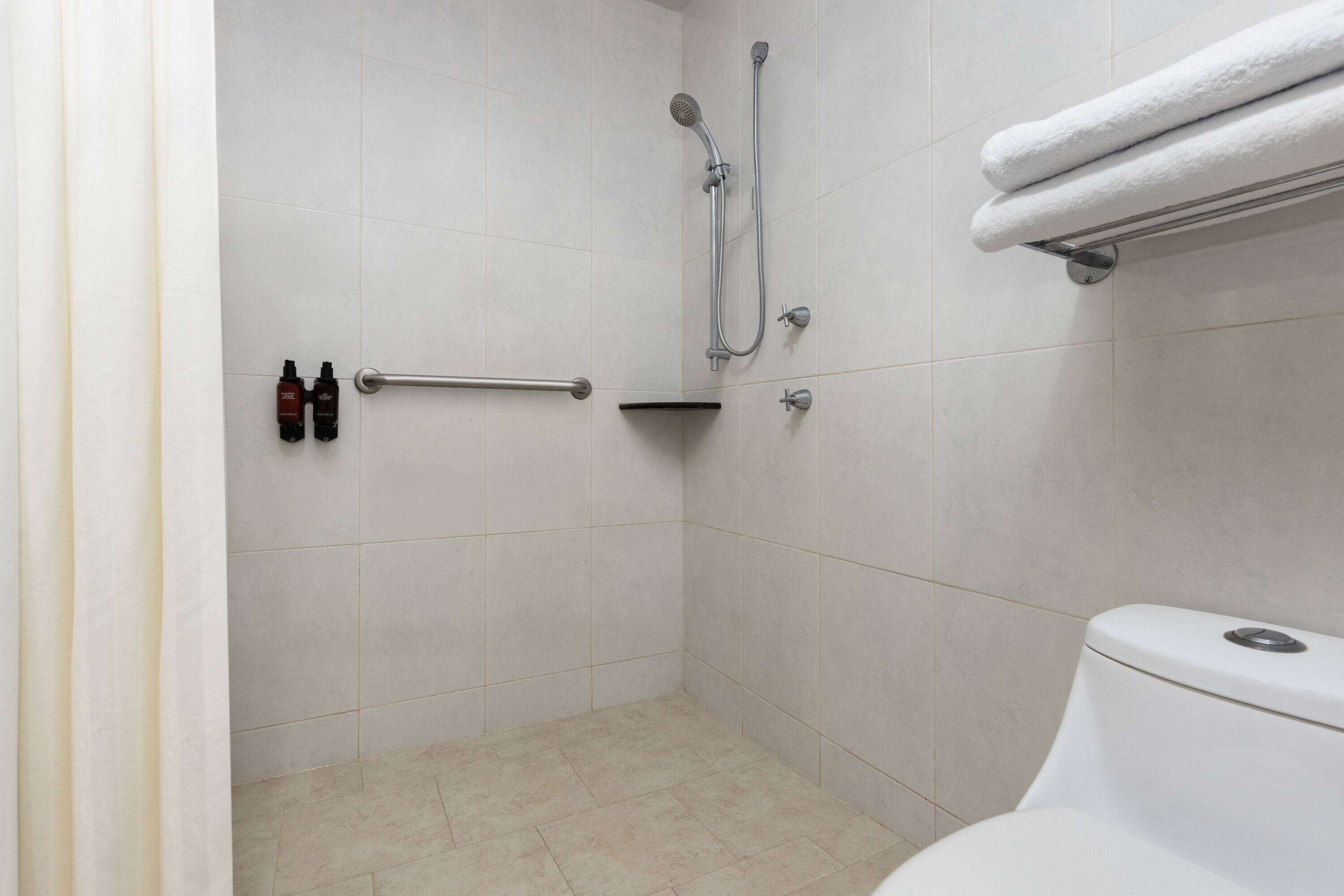 A bathroom with a shower, a toilet, and a towel rack.