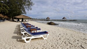 A beach with lounge chairs lined up, a pier extending into the water, and a thatched-roof structure. - Independence Hotel by Dara (Sihanoukville)