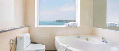 Un baño con inodoro, bañera y ventana con vista al mar.