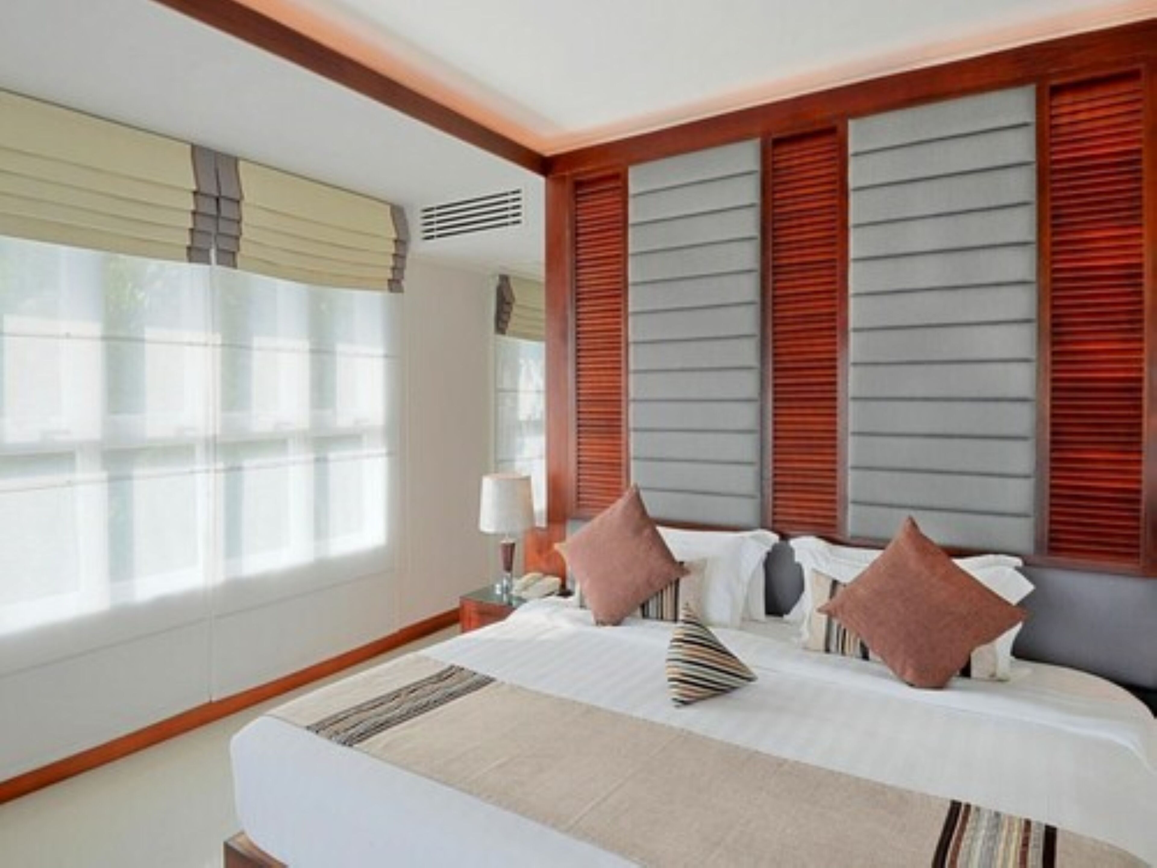 Habitación de hotel con una cama grande, cabecera de madera y una ventana con persianas.