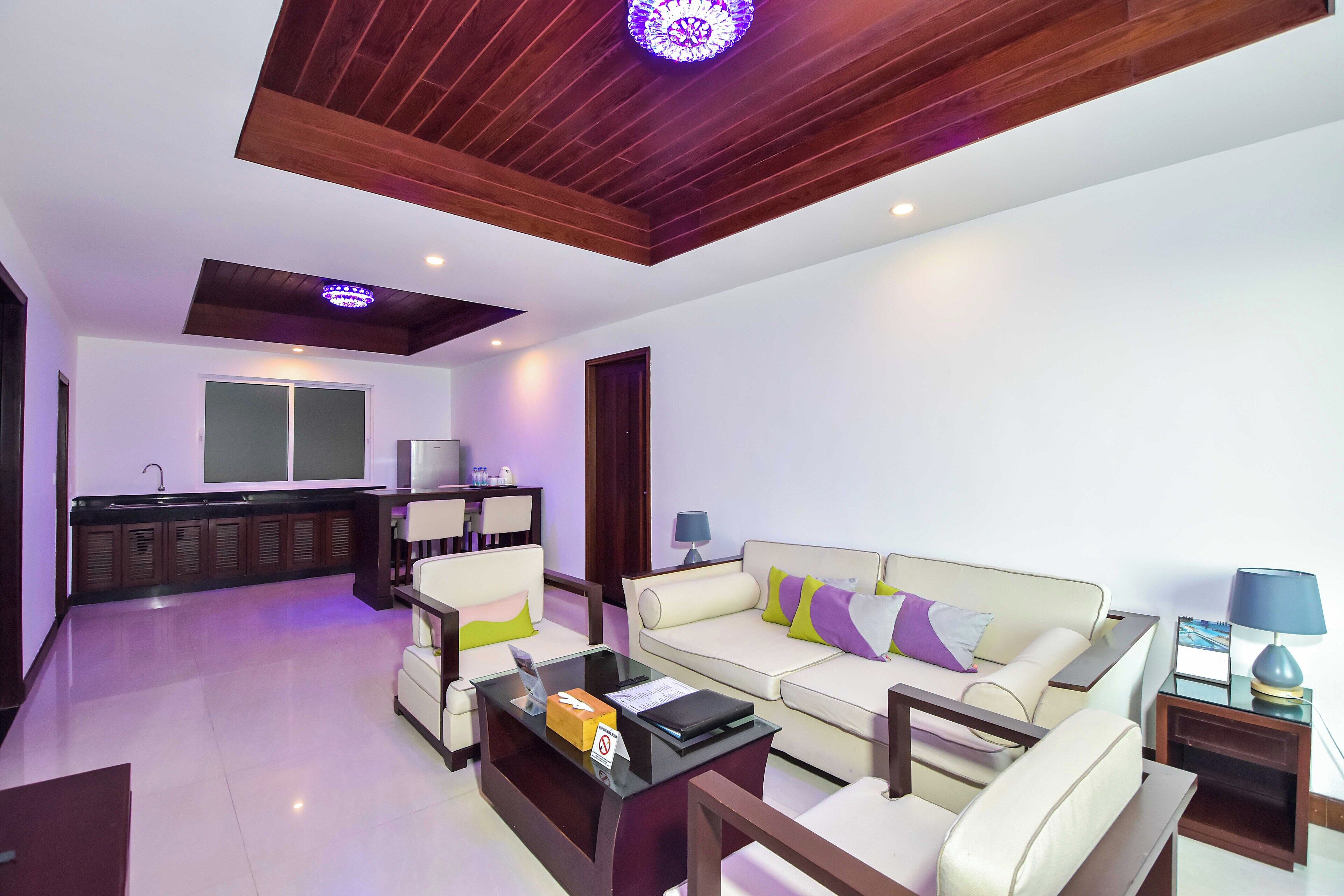 A modern living room with a sofa, coffee table, and a kitchen area in the background.