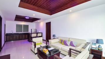 A modern living room with a sofa, coffee table, and a kitchen area in the background.