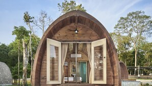 A wooden arched structure with an open entrance, a bed, and a bathroom visible inside. - Independence Hotel by Dara (Sihanoukville)