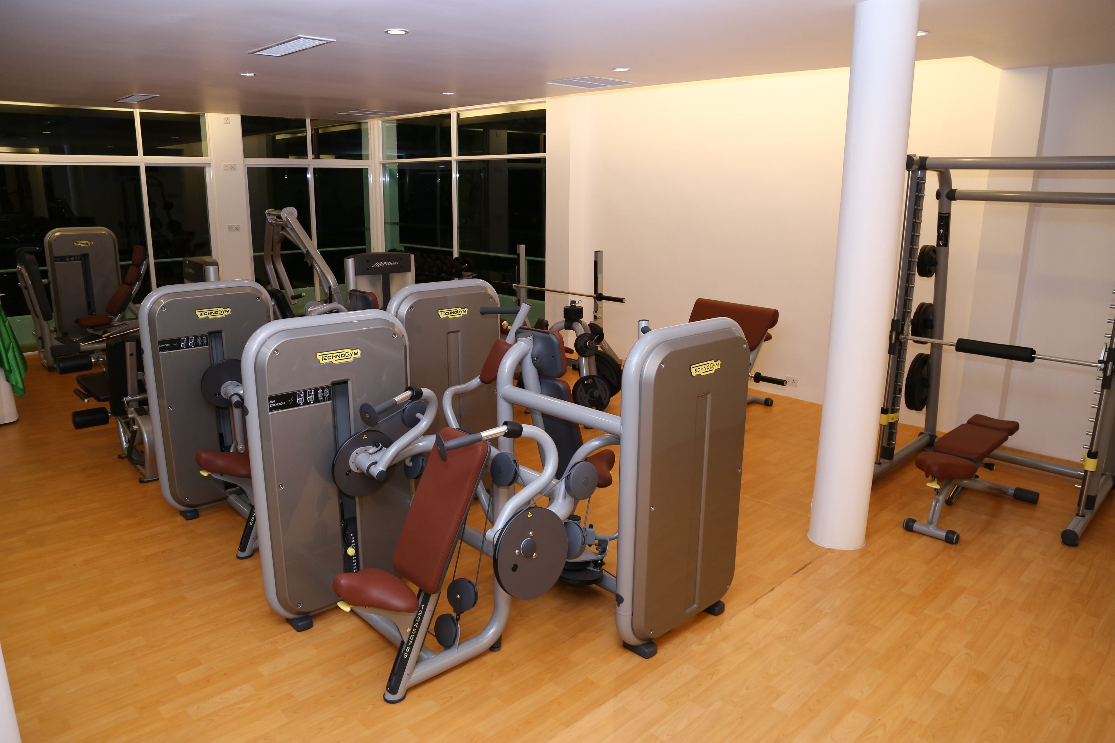 A gym with cardio machines, weightlifting equipment, and a bench.