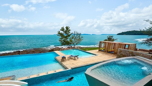 A swimming pool with a view of the sea, a wooden deck, and a hot tub. - Independence Hotel by Dara (Sihanoukville)