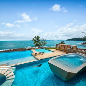 Ein Pool mit Meerblick, eine Holzterrasse und ein Whirlpool.