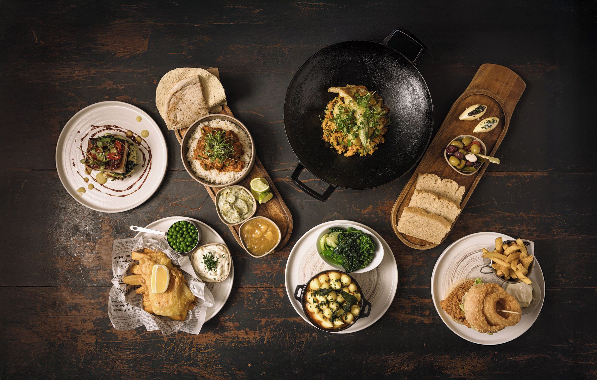 A variety of dishes including fish and chips, a bowl of peas, and a pan with scrambled eggs.