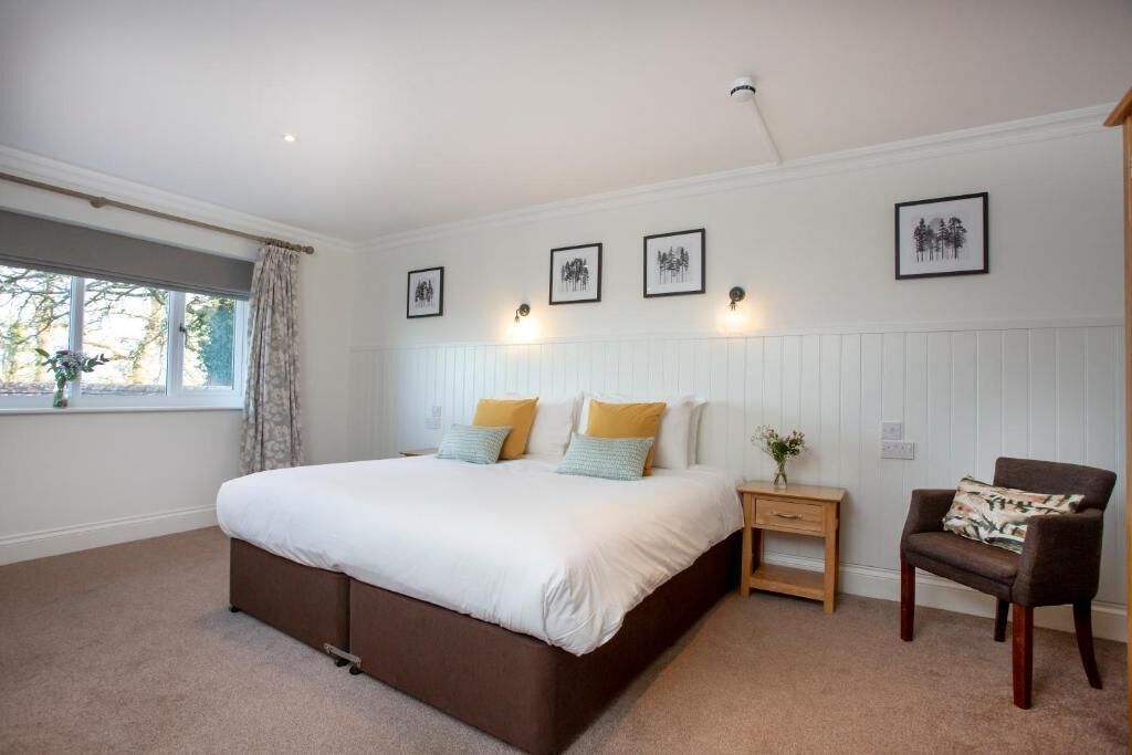 A bedroom with a large bed, a nightstand, a chair, and framed pictures on the wall.
