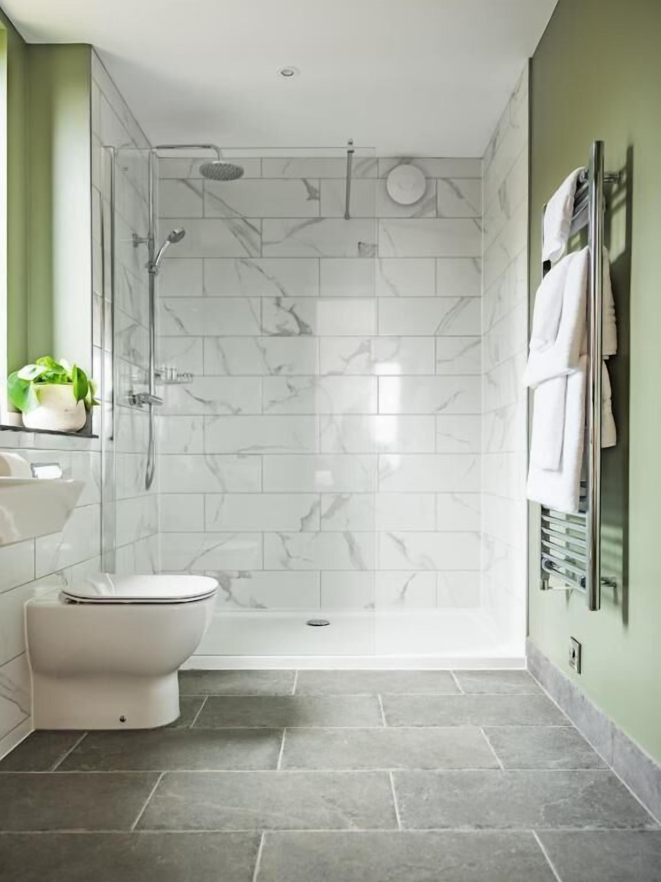A modern bathroom with a glass shower enclosure, a white toilet, a sink, and a towel rack.