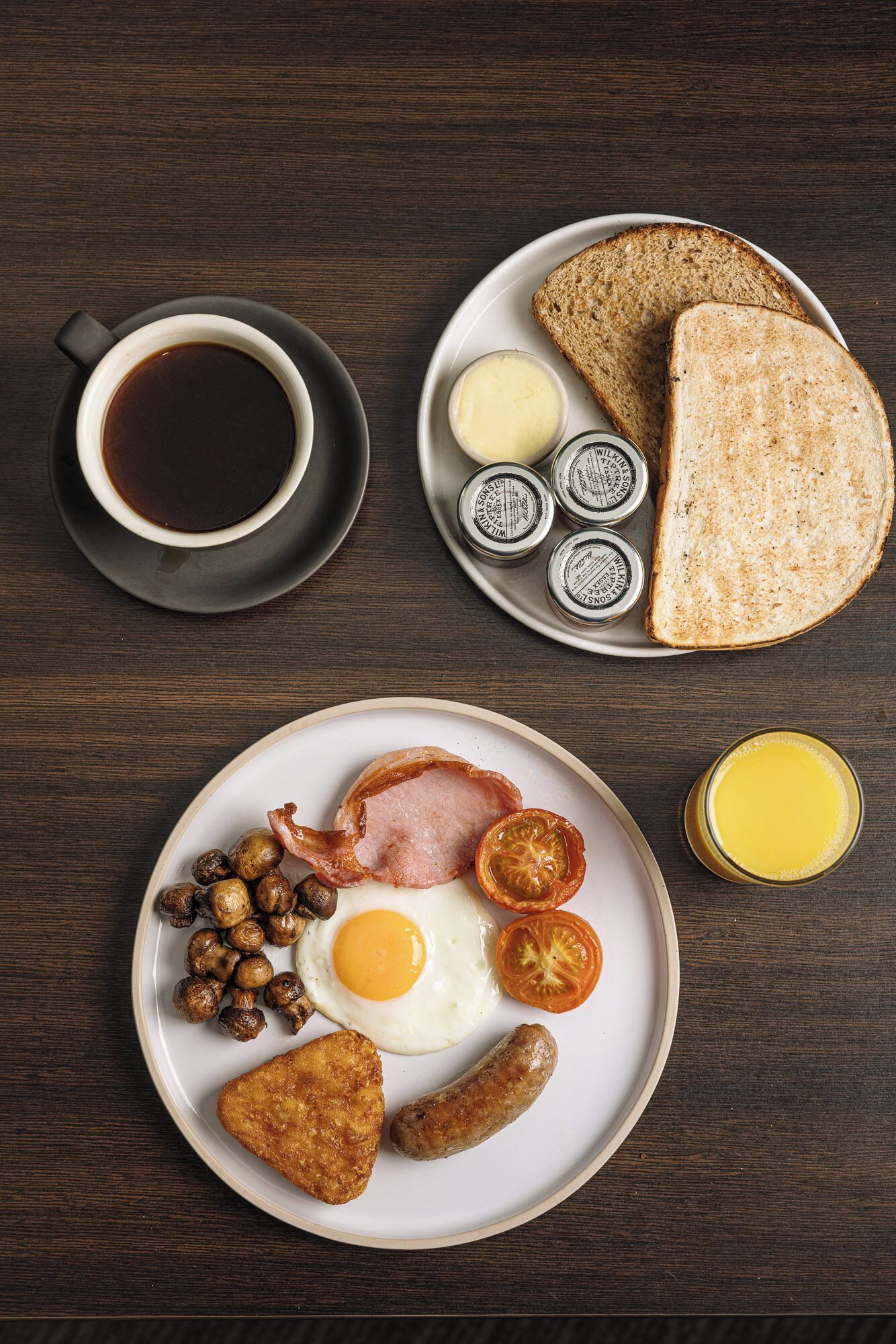 Une assiette de petit-déjeuner comprenant des œufs, du bacon, des champignons, des saucisses et des toasts.
