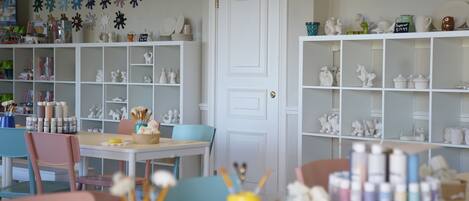 A room with white shelves filled with decorative items, a white door, and a table with art supplies.