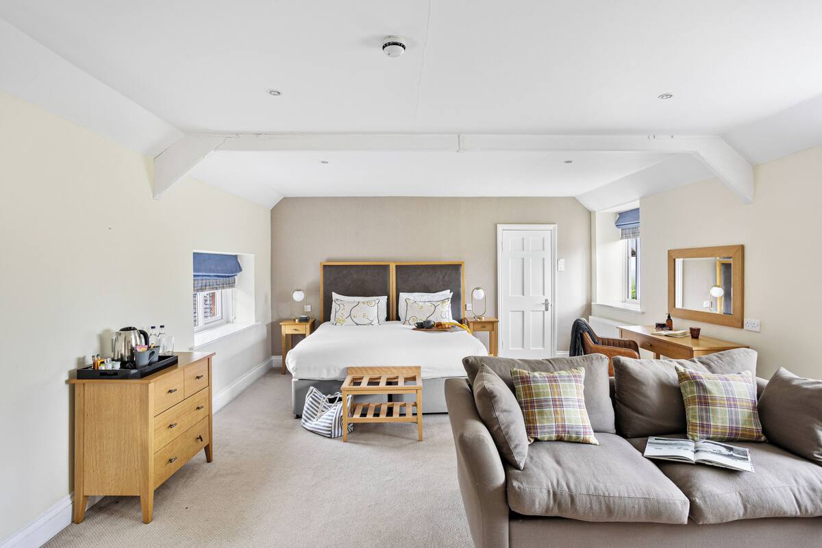 Une chambre spacieuse avec un grand lit, une commode en bois, un canapé et un bureau avec une chaise.