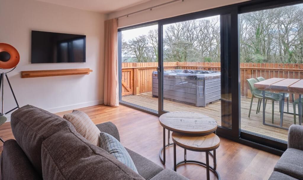 En moderne stue med sofa, sofabord og fjernsyn monteret på væggen.
