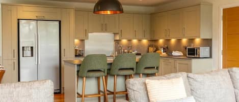 A modern kitchen with a central island, bar stools, and a dining area with a sofa.